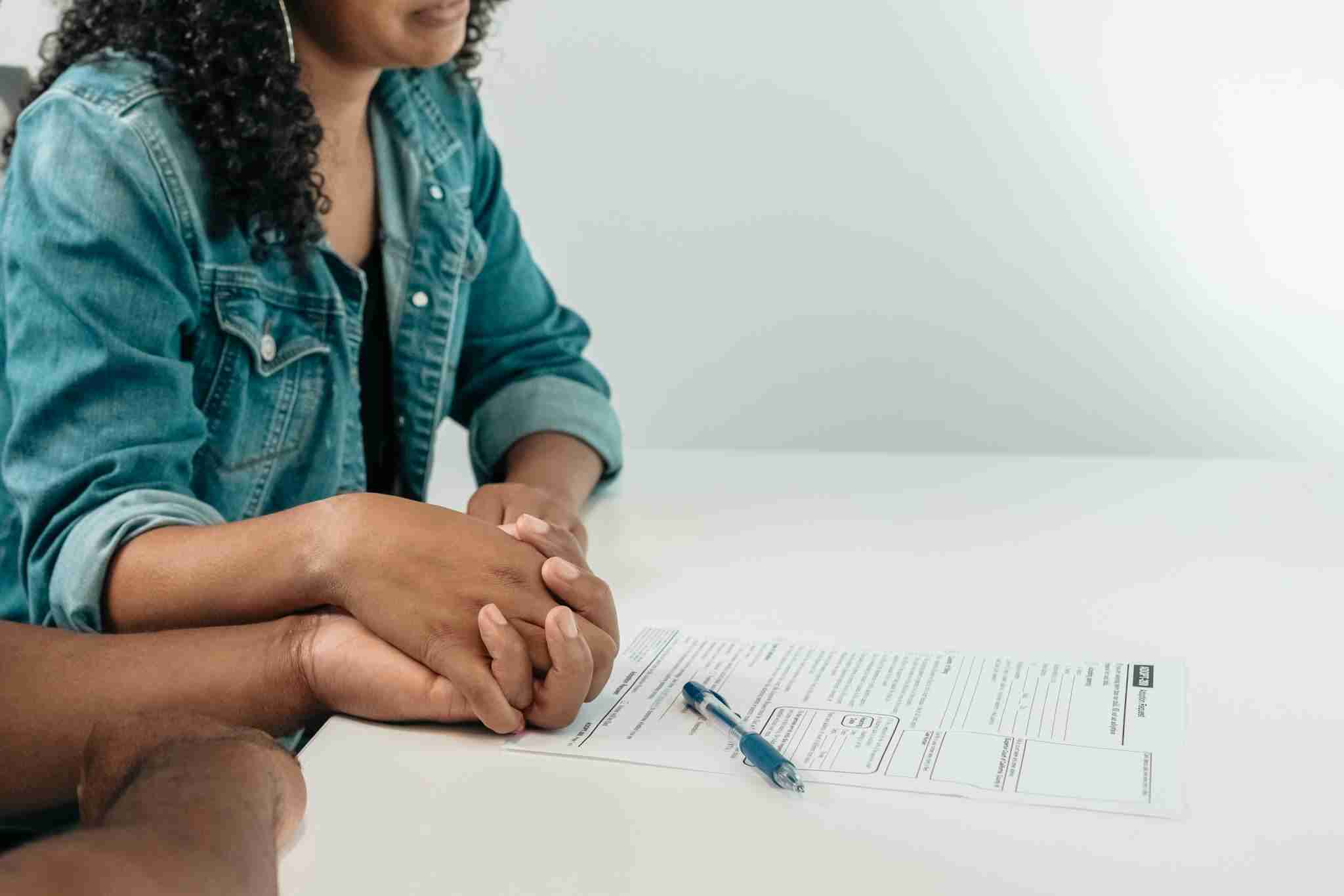Couple holds hands over adoption papers, symbolizing family unity and support in a legal setting.
